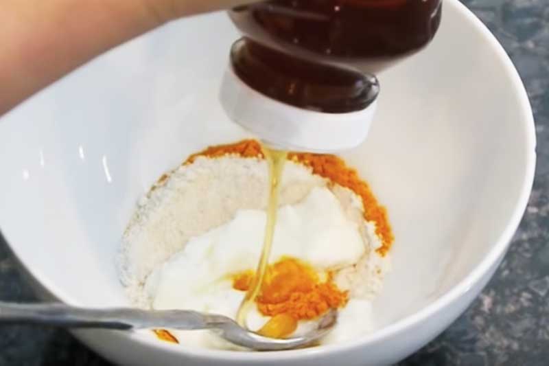 honey being squeezed over ingredients in a white bowl