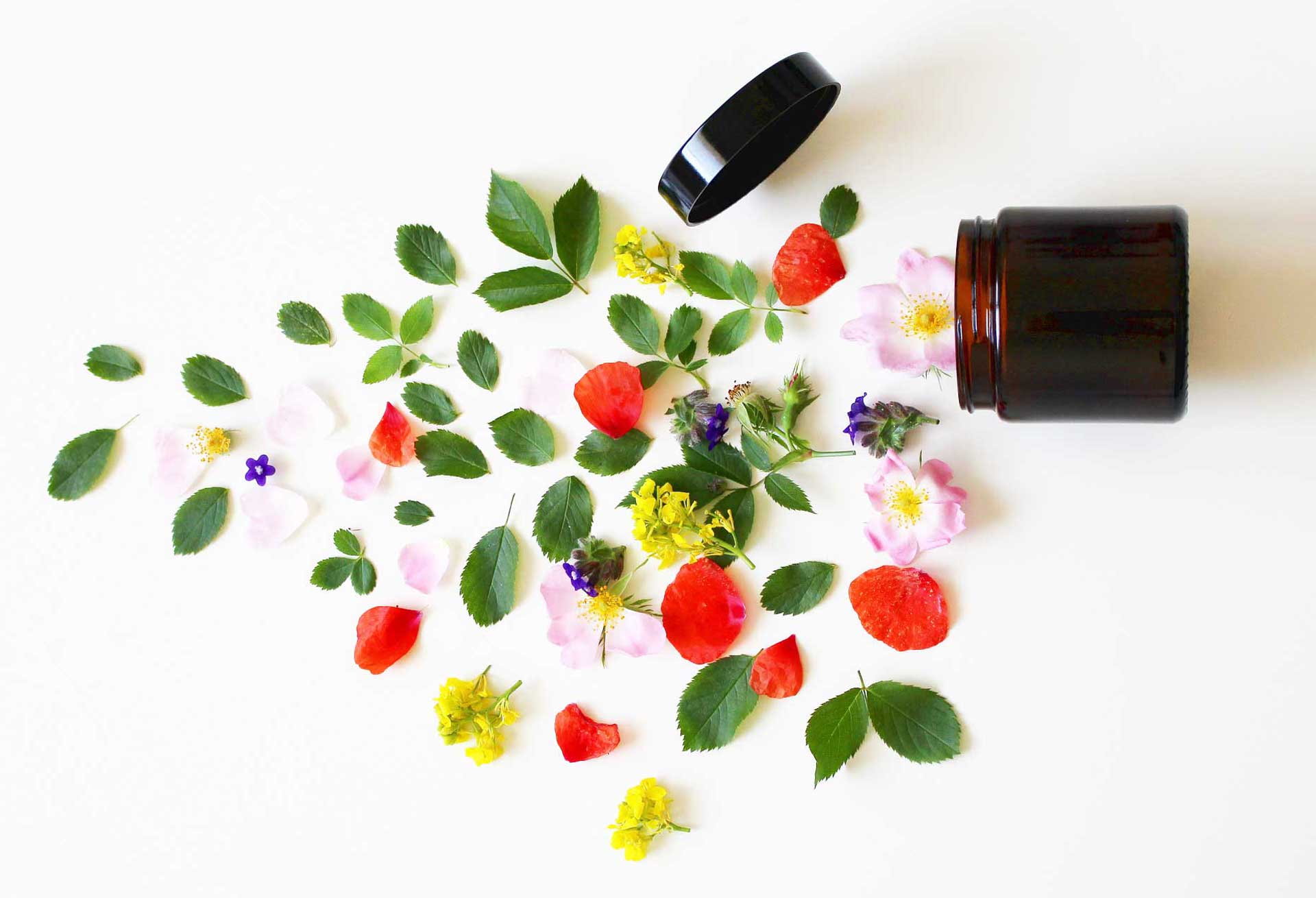 a brown cosmetics jar on it's side with leaves and flowers spilling out